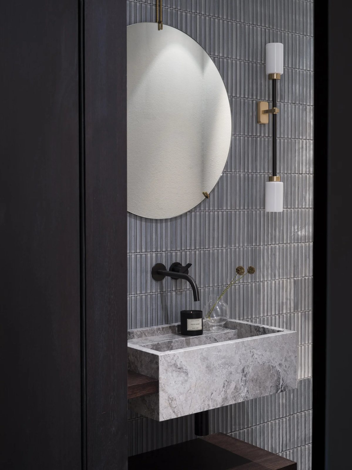 Elegant guest bathroom with vertical finger grey tiles, round mirror, and a minimalist marble basin