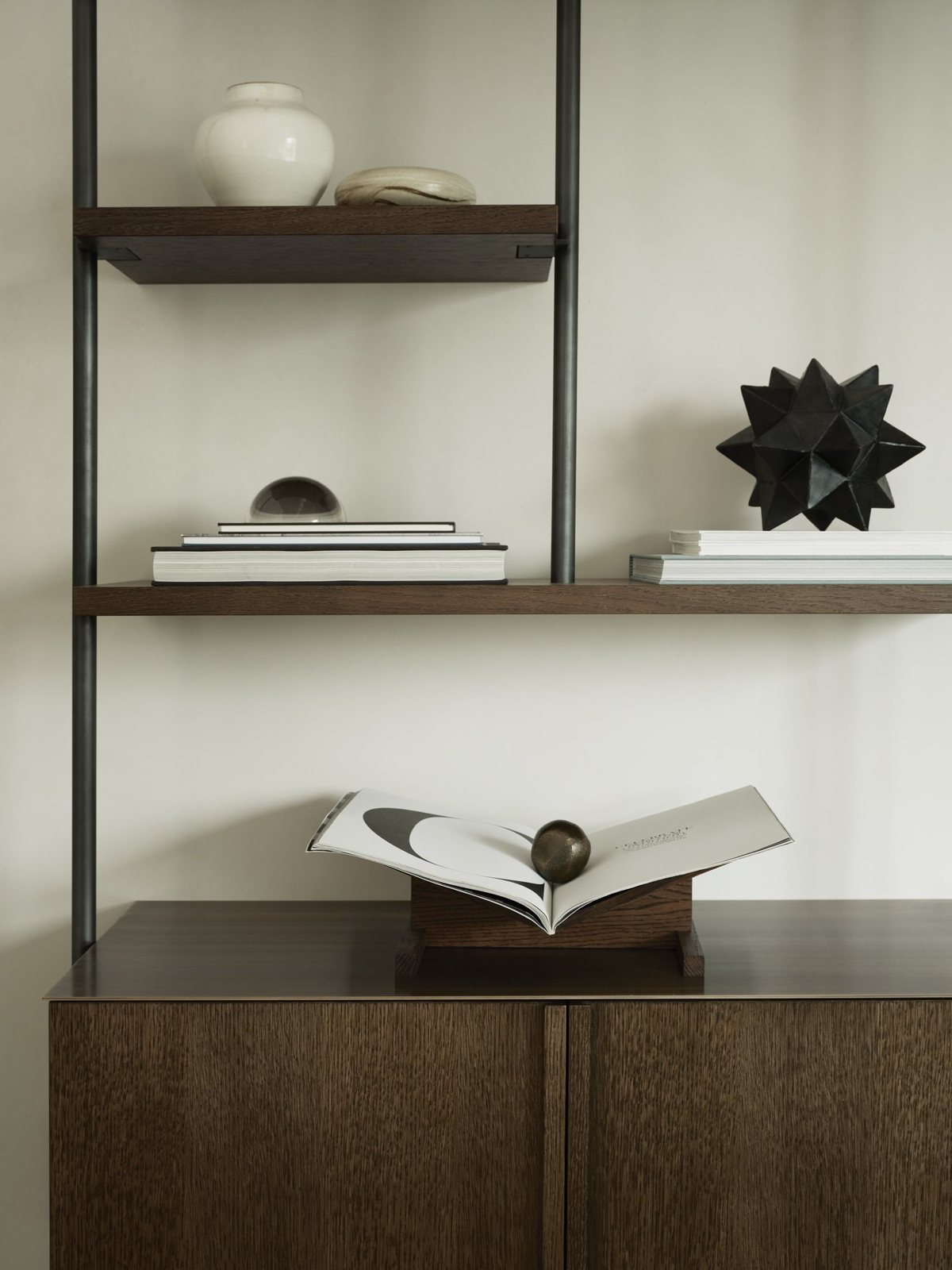 Detail view of modern wall-mounted wood and metal shelves displaying books, ceramics and geometric sculptures