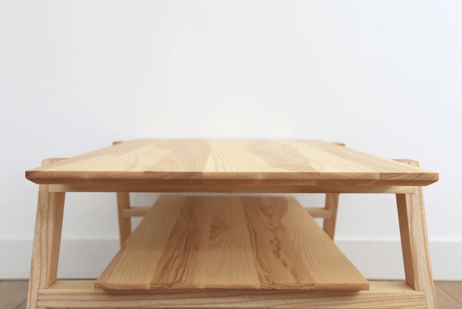 Minimalist coffee table in solid ash with angled legs and shelf
