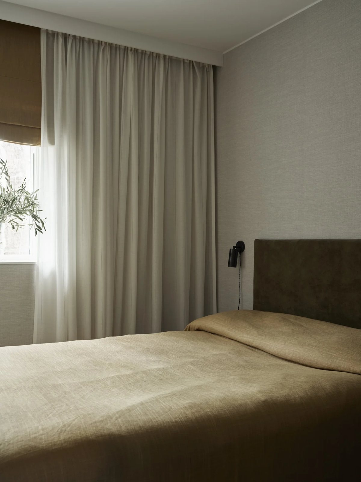 Brown linen bedding with olive headboard and sheer curtains