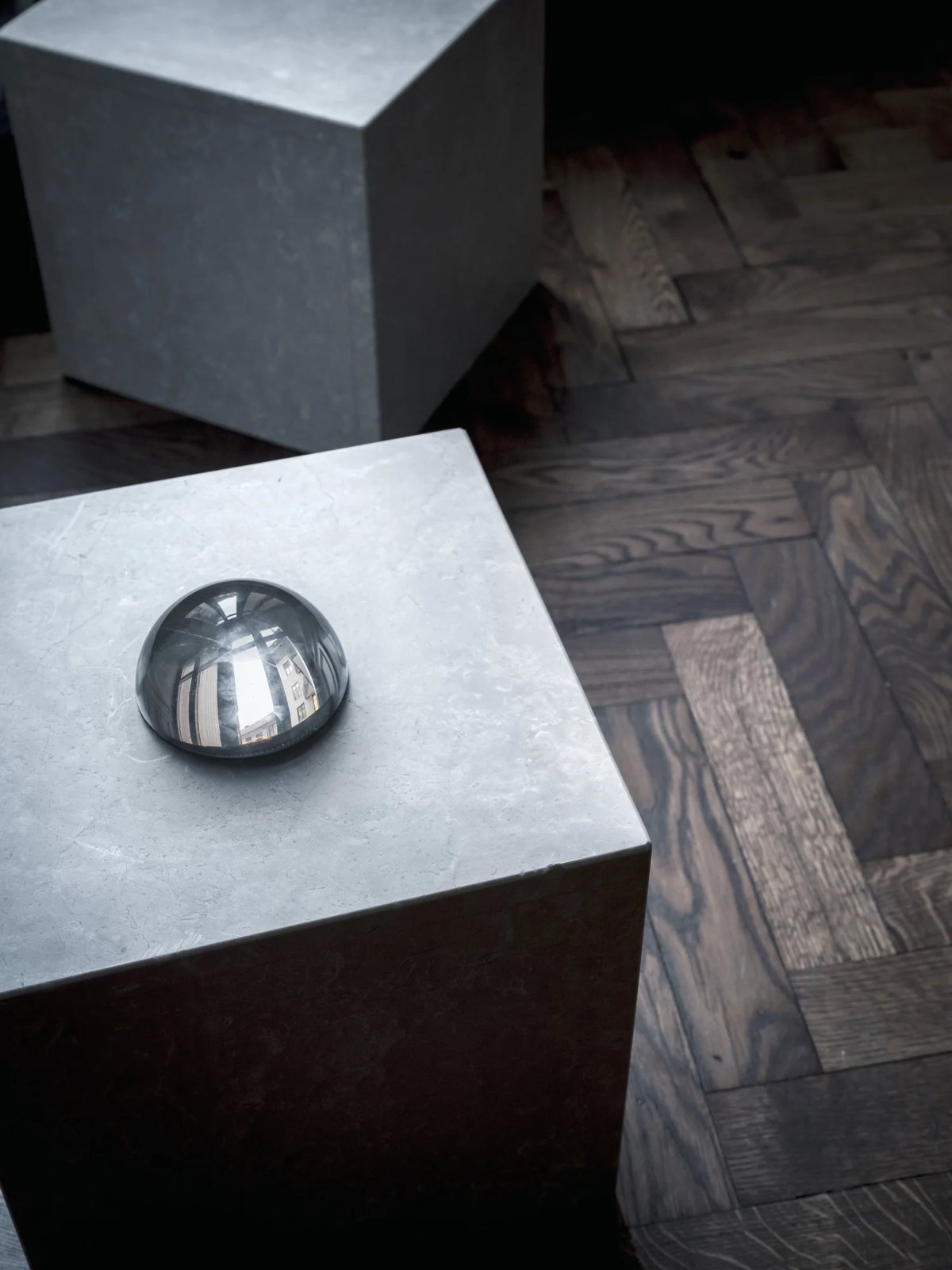 Marble cubes with reflective orb atop parquet floor.