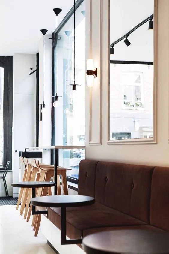 Window-side bar with hanging lights and velvet seating.