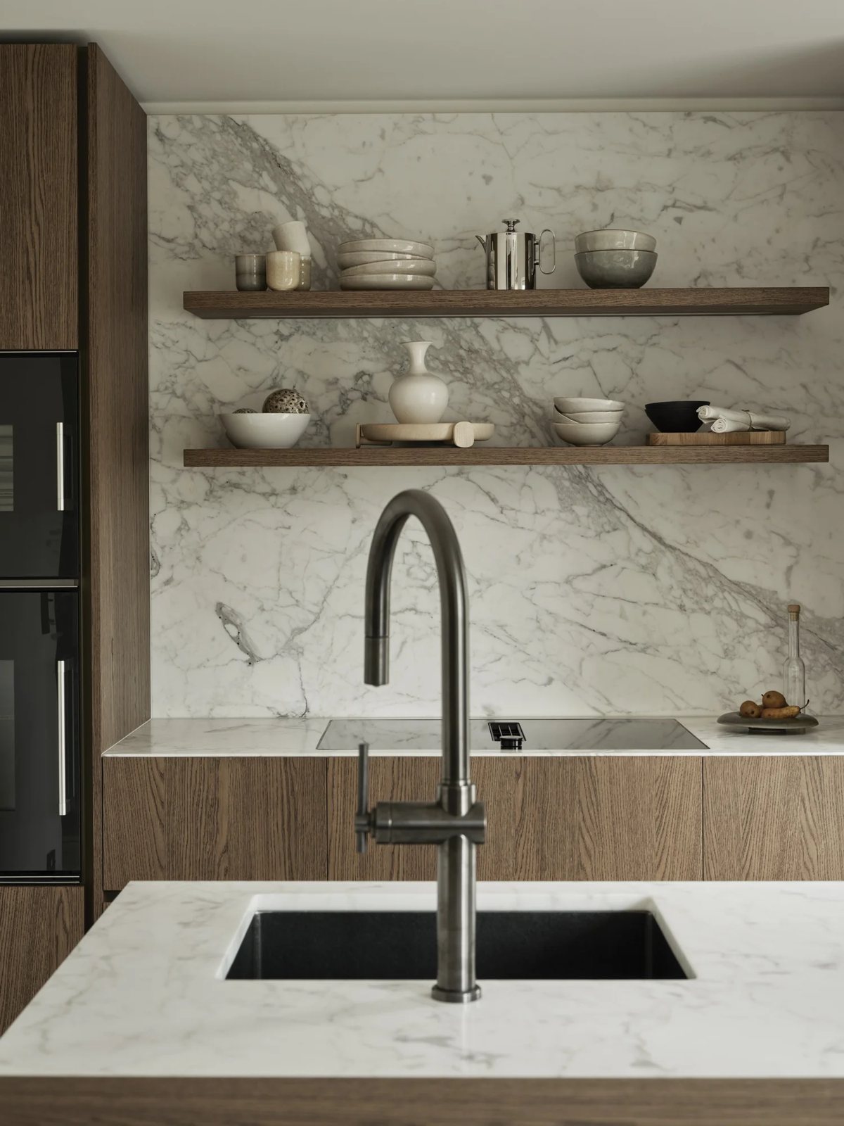 Close-up of marble kitchen backsplash with floating wood shelves and ceramics