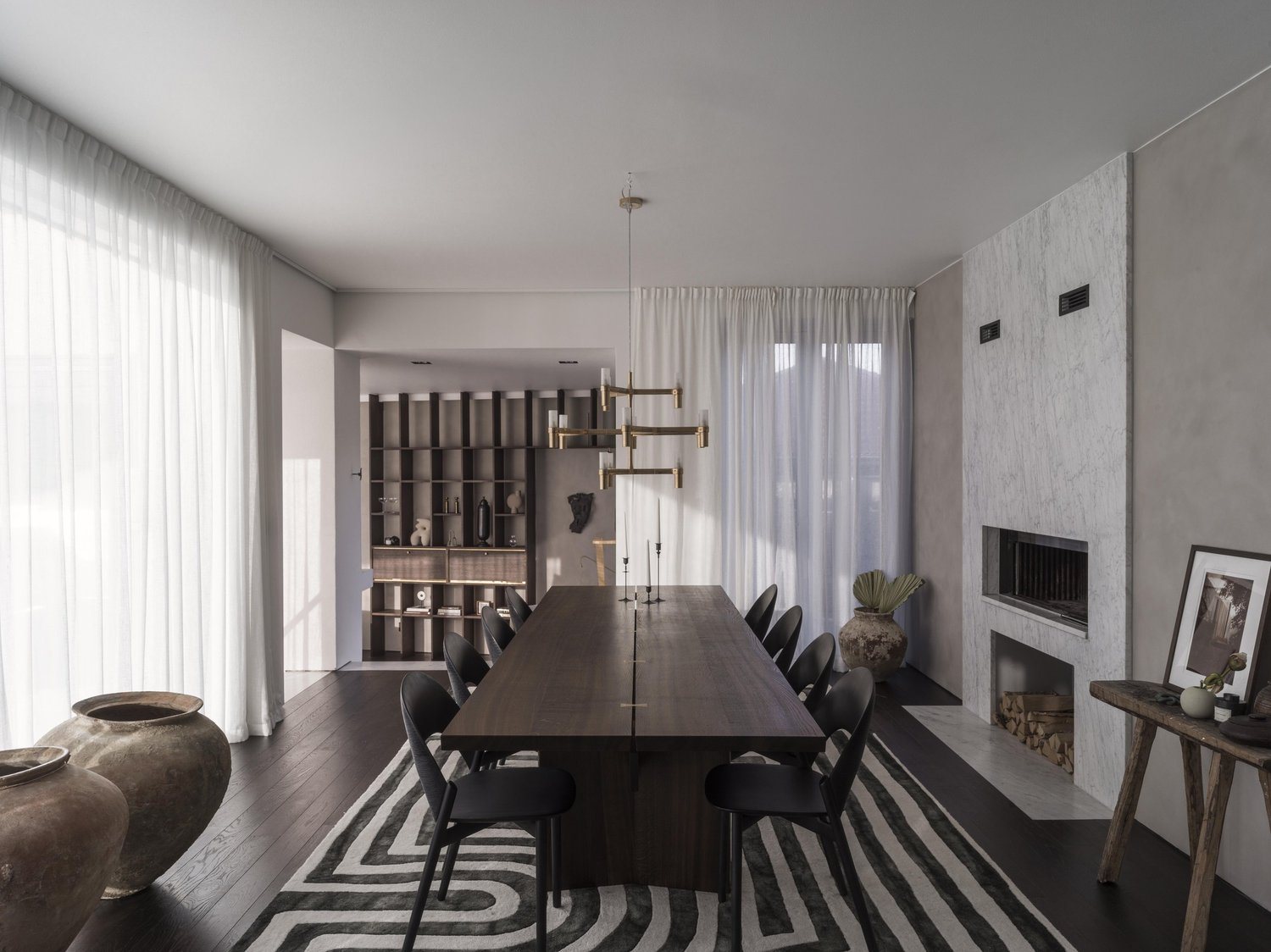 Spacious dining area with a dark wood table, graphic rug, and fireplace.