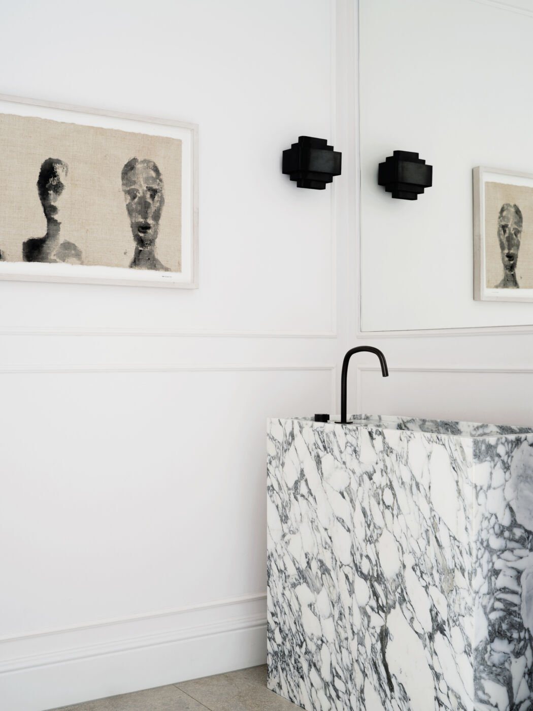 Elegant marble washbasin with abstract artwork and matte black fixtures.