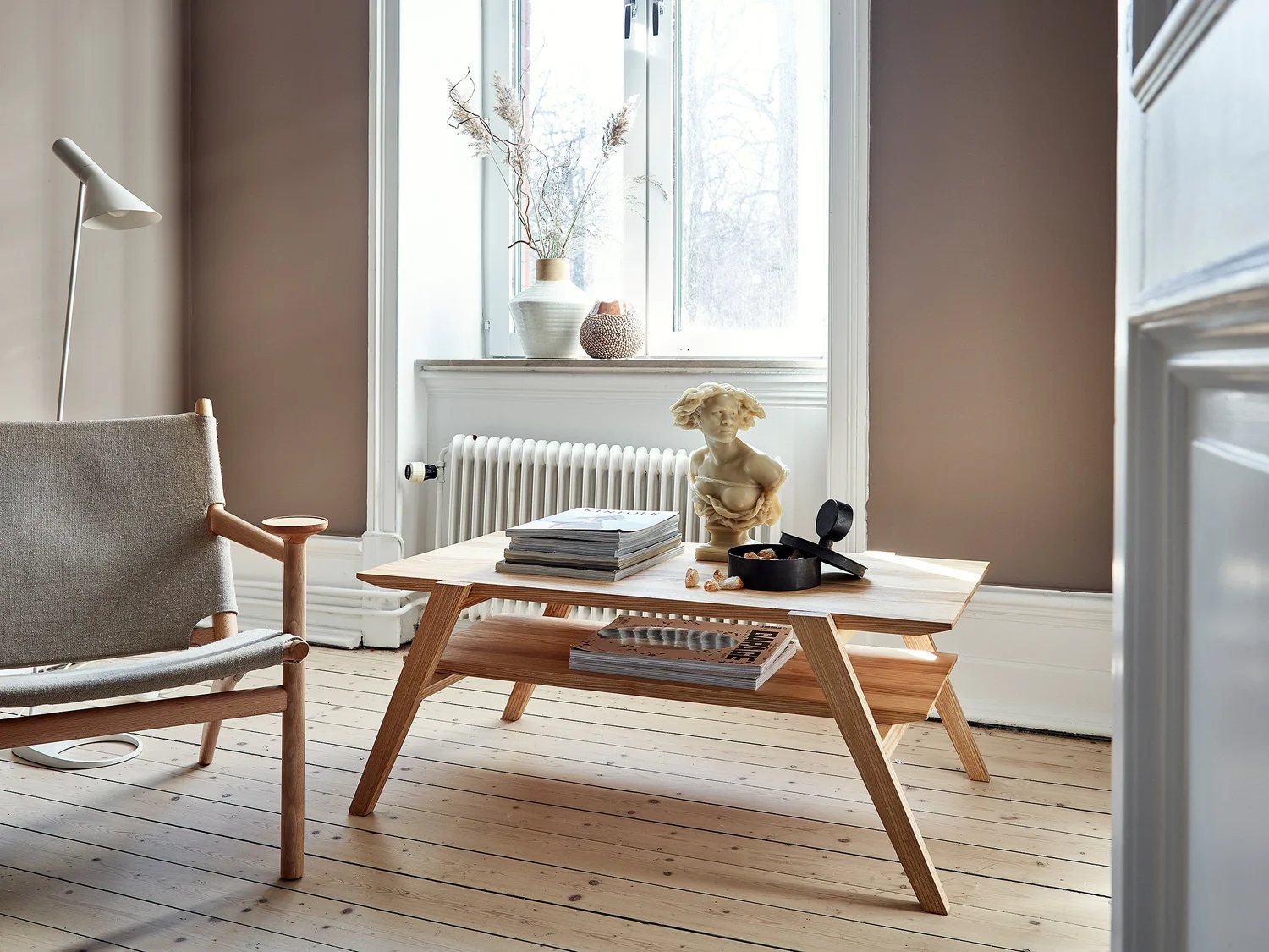 Coffee table with sculptural styling next to lounge chair and window