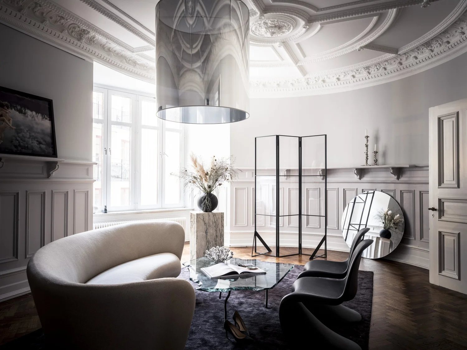 A rounded salon with high ceiling, sculptural furniture and soft light.