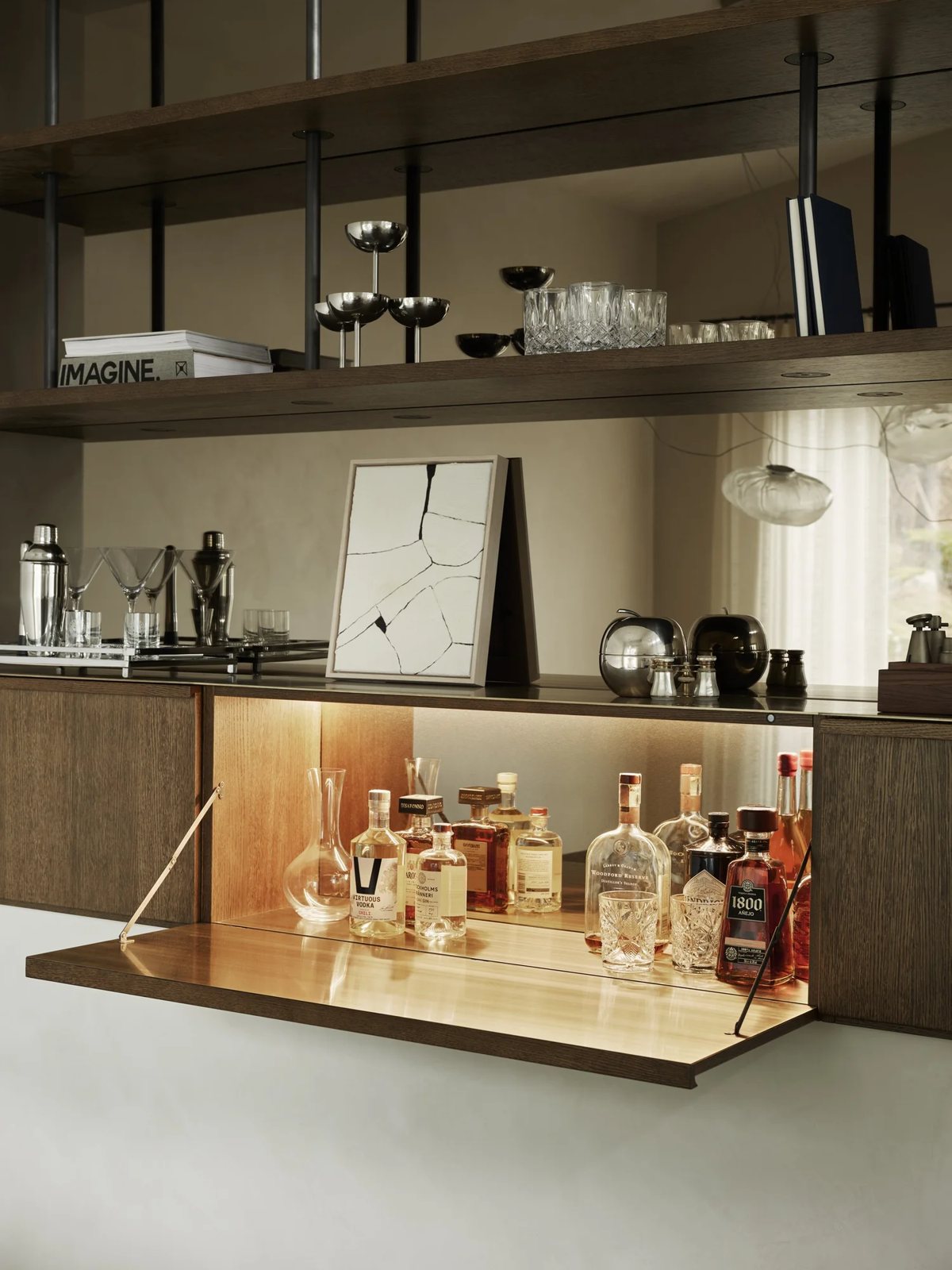 Close-up of hidden home bar with brass shelf and liquor bottles inside a dark wood cabinet