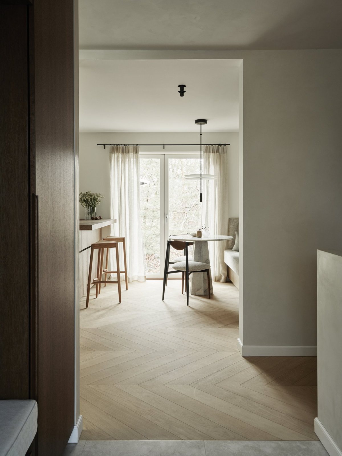 Open dining nook with chevron oak floors and full-height curtains