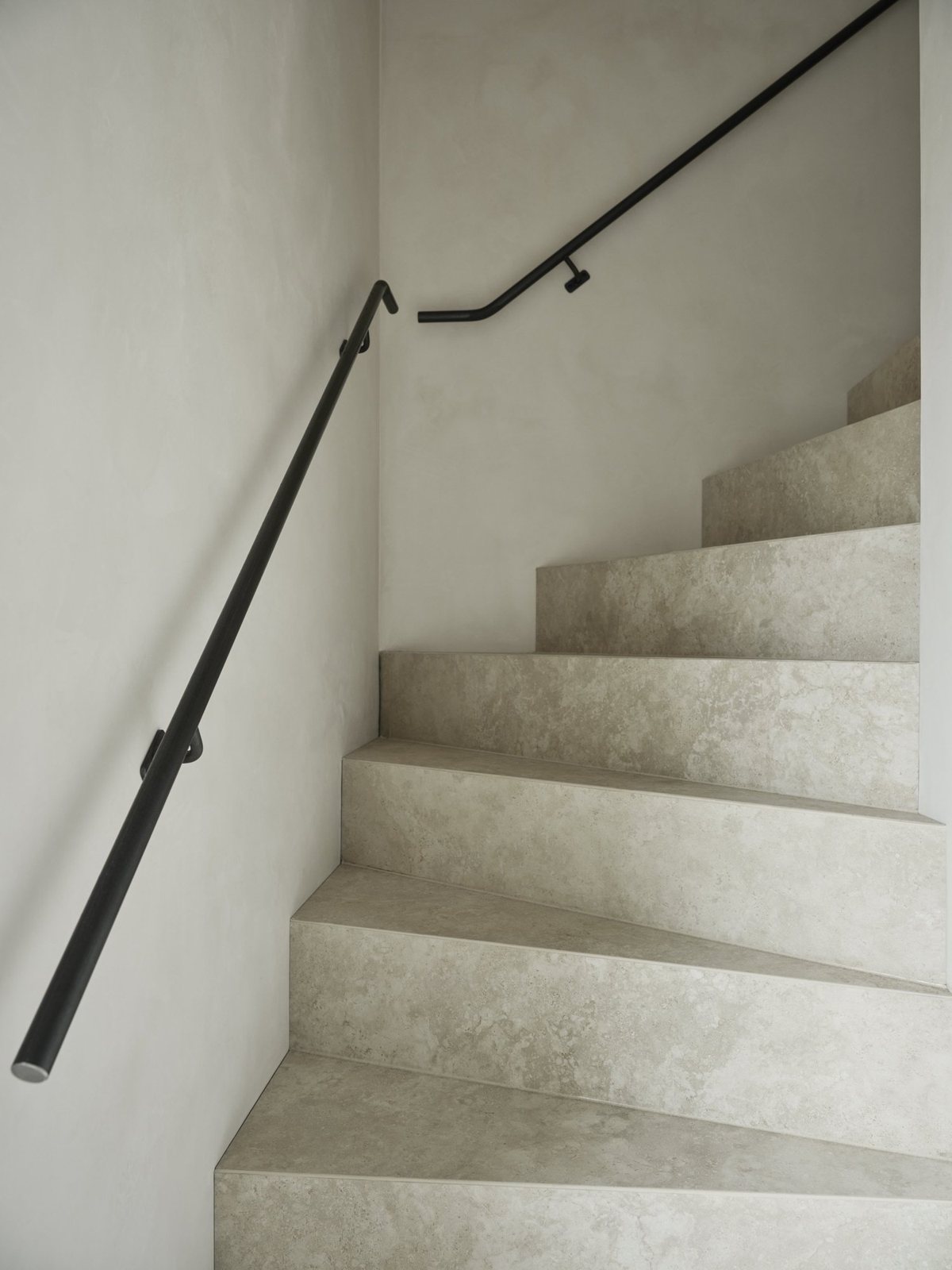 Stone steps with black iron handrail and smooth plaster walls