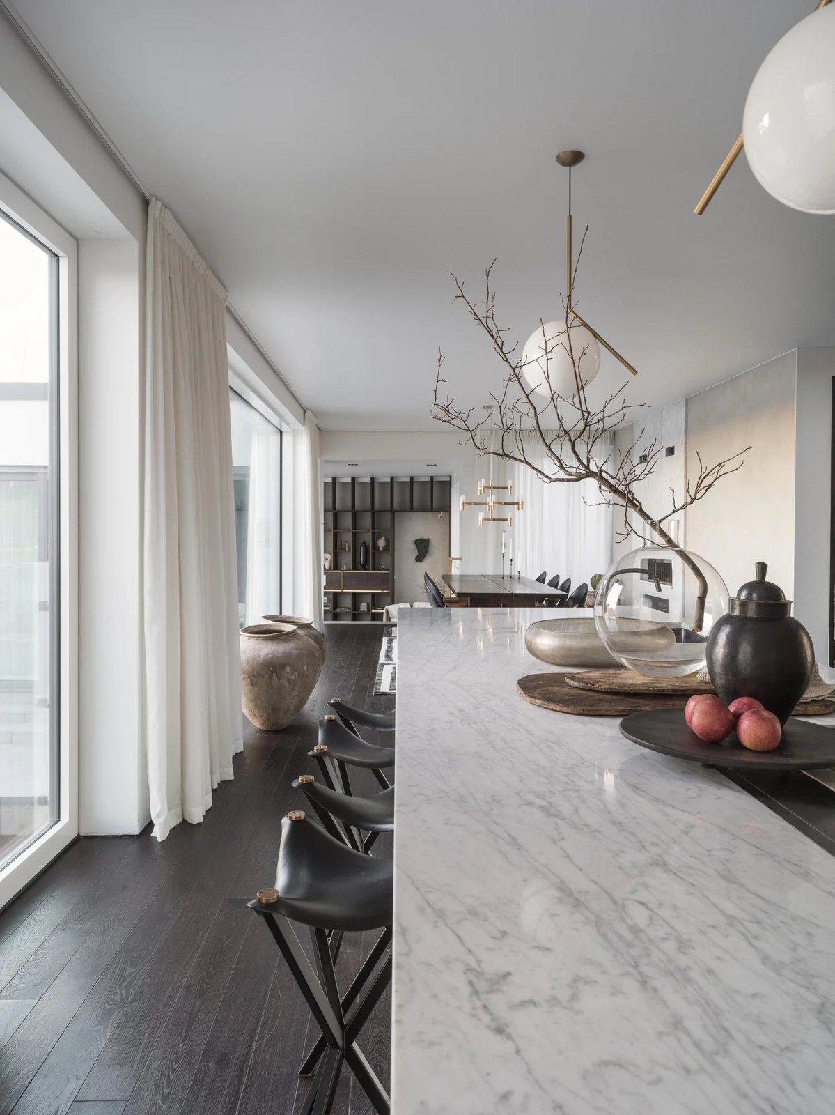 White marble kitchen island with black leather bar stools and rustic wooden decor pieces.