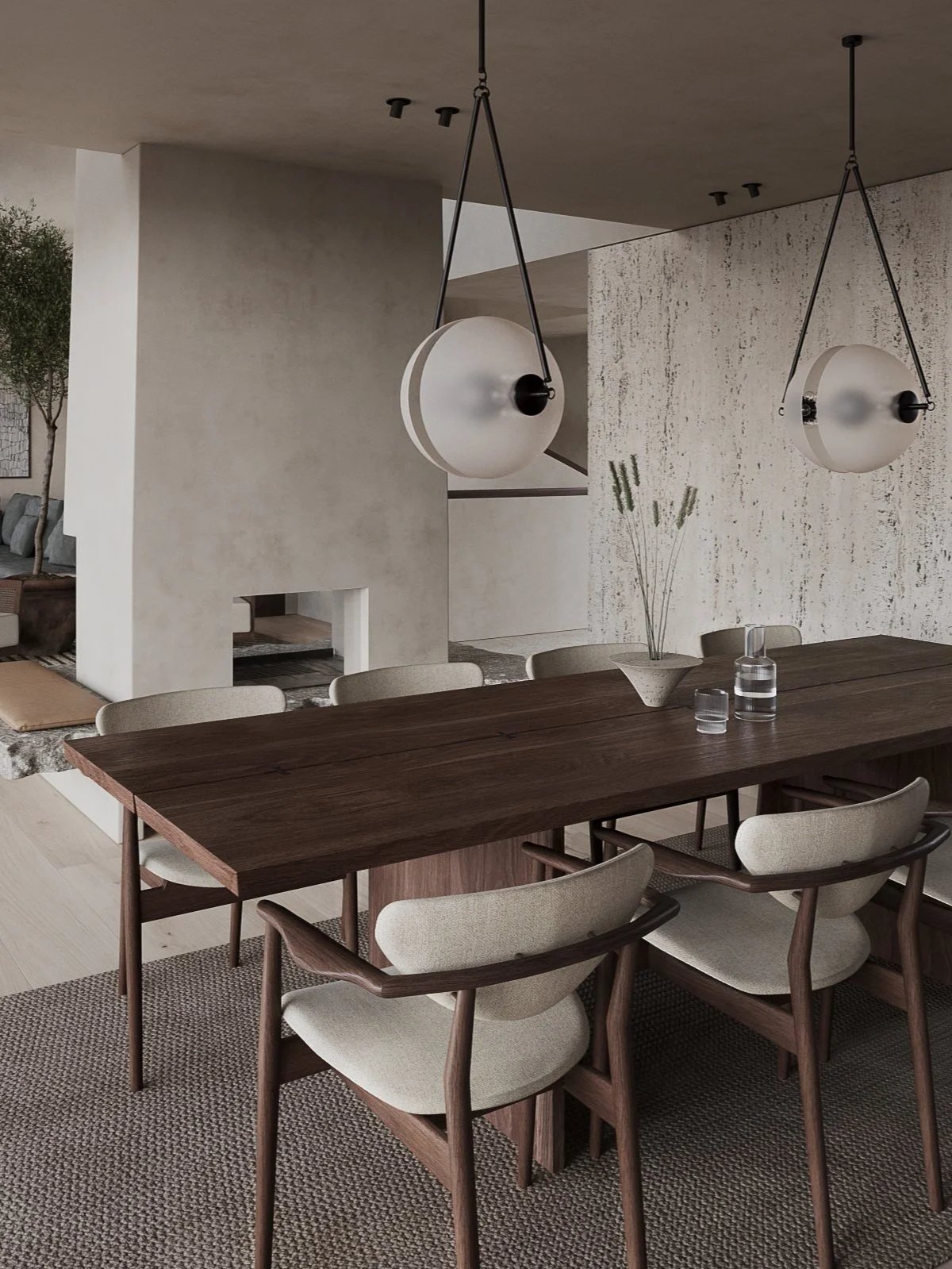 Open-plan dining room with solid wood table and sculptural lighting and fireplace, leading to a soft-toned lounge.