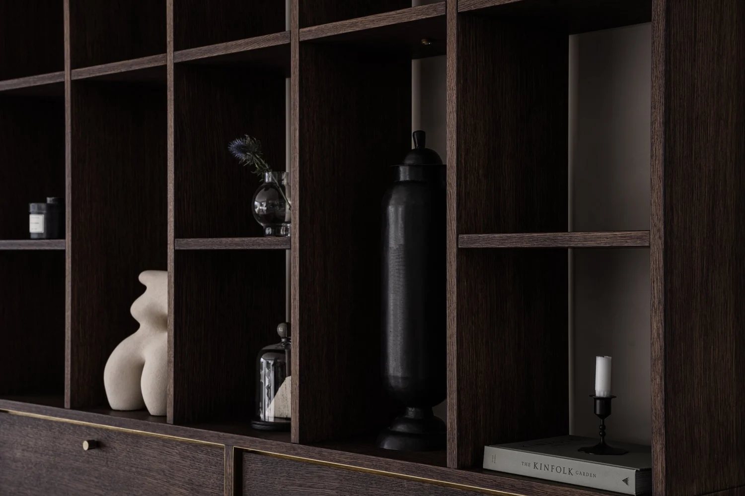 Dark oak bookshelf with ceramics, glass, and minimalist styling