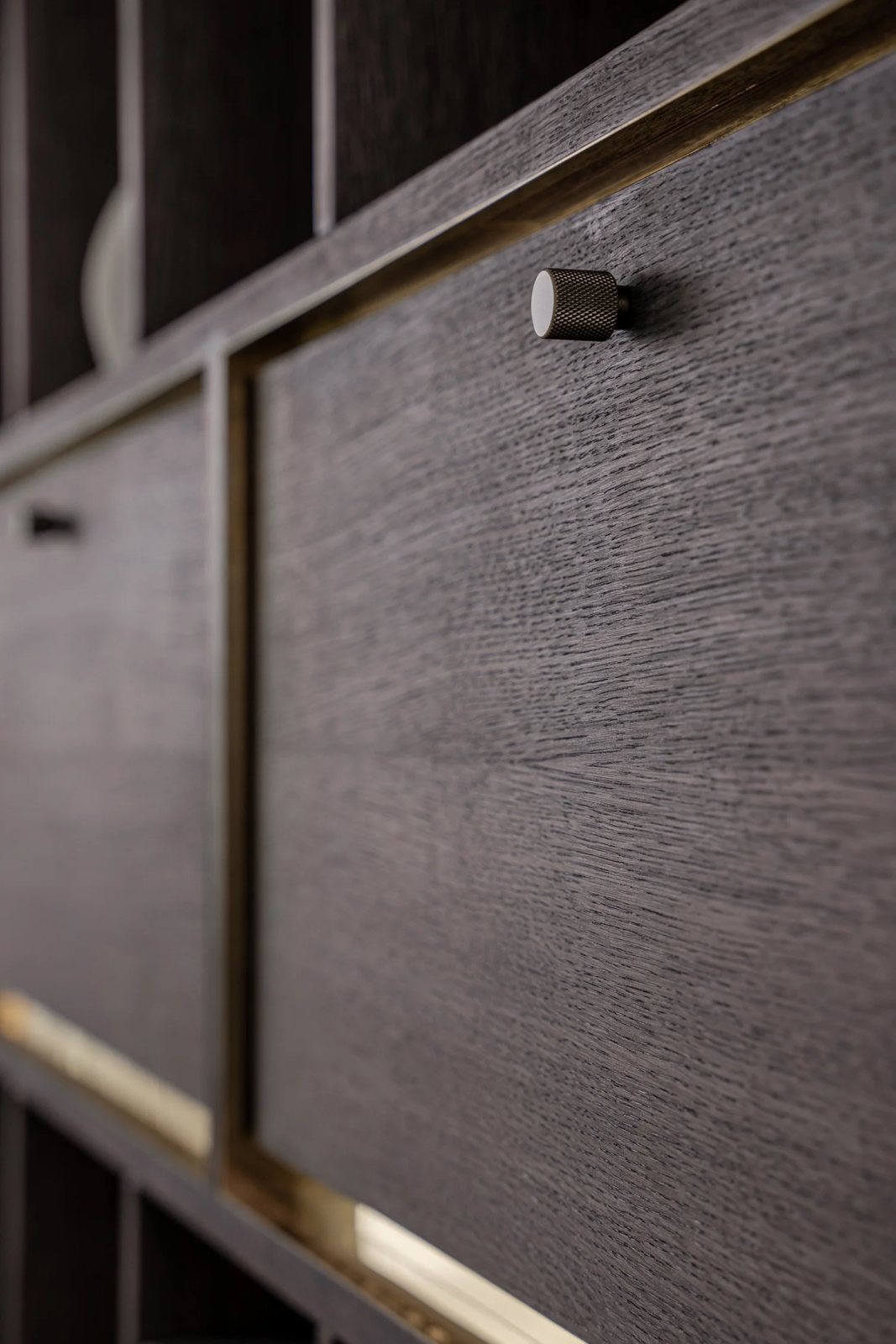 Close-up of knurled knob on dark oak cabinet with brass trim