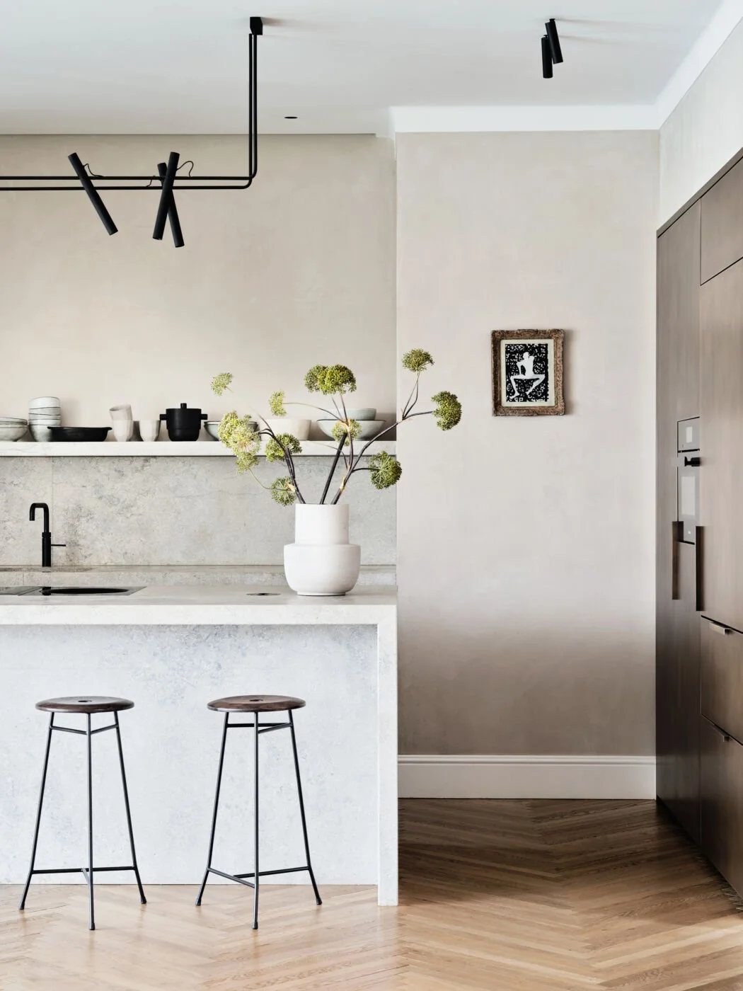 Light-toned kitchen island with modern stools and ceramic decor.