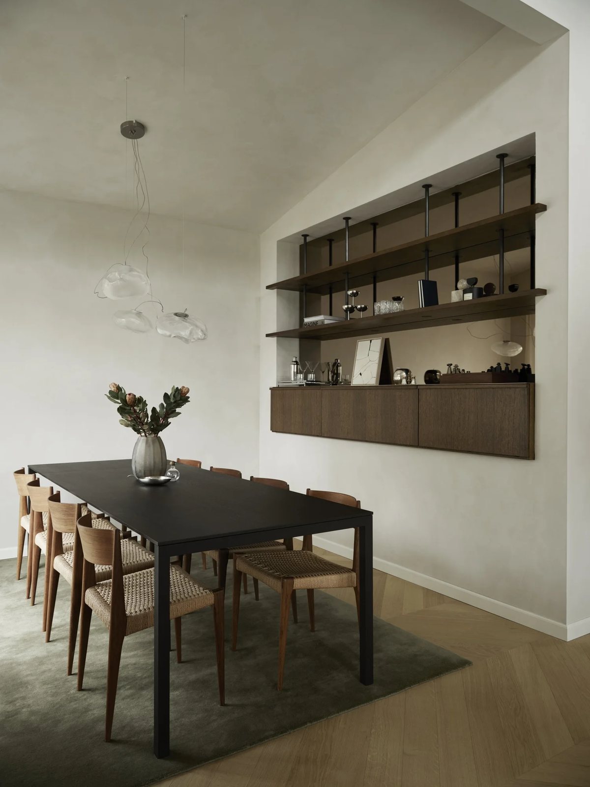 Custom-built floating shelves and concealed bar cabinet in dining space with natural plaster walls