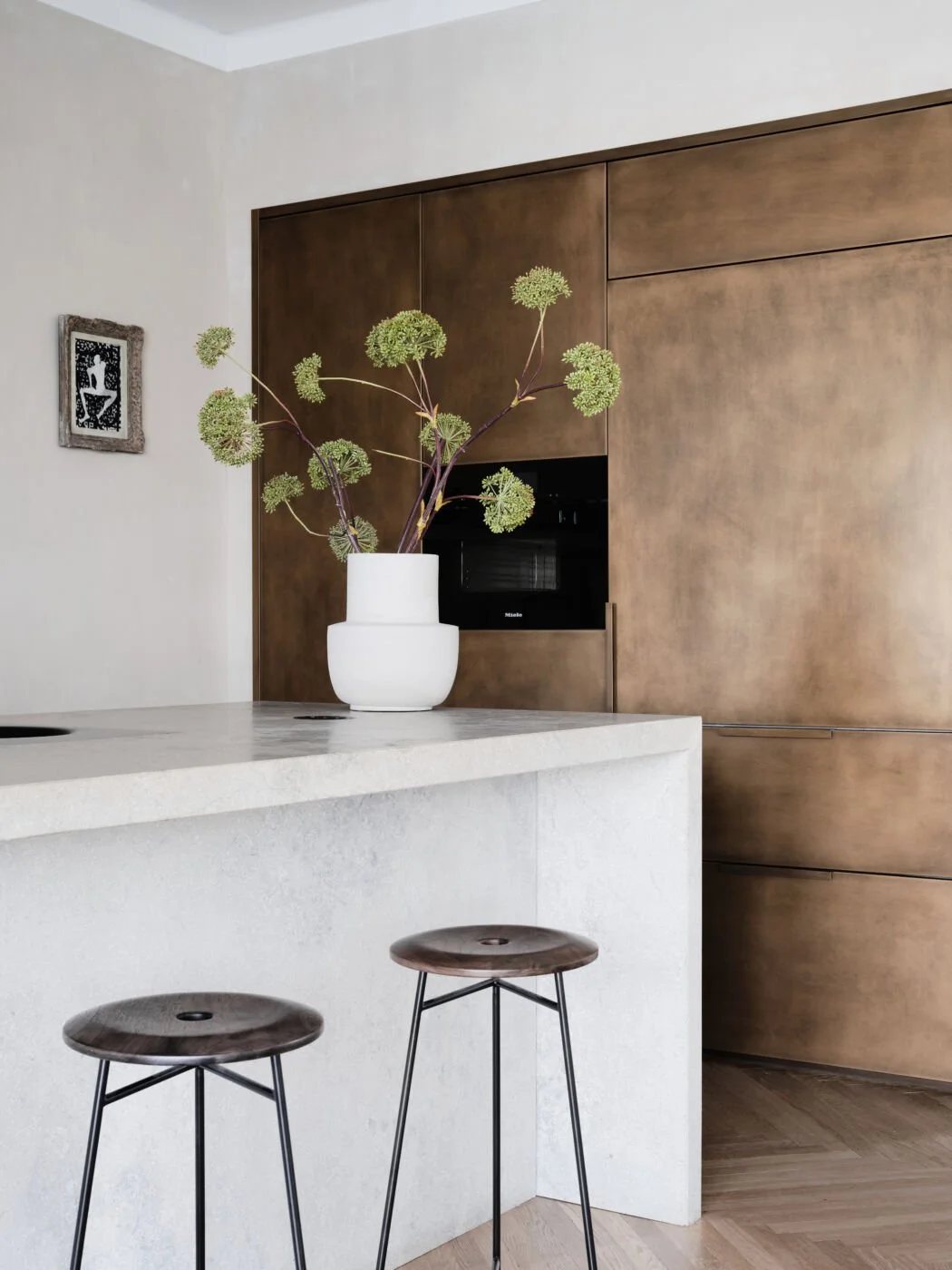 Brass-fronted kitchen cabinetry with light stone countertop and botanical styling.