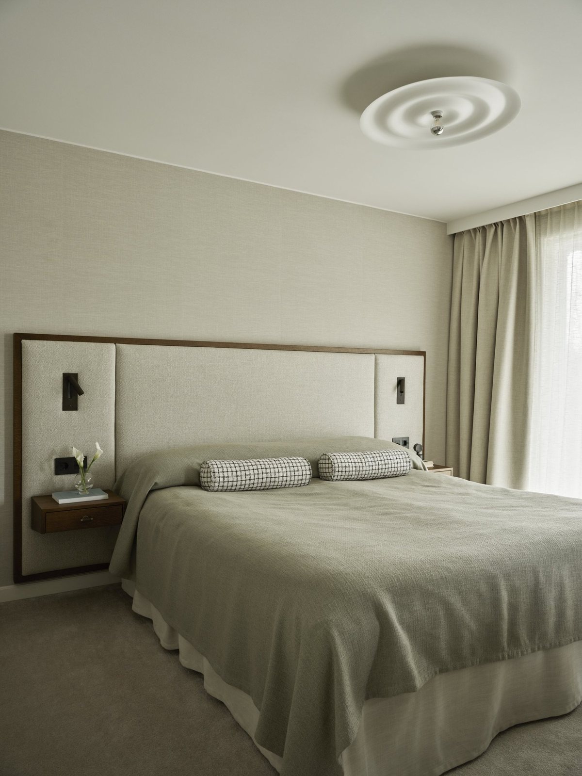 Neutral bedroom with wall-mounted nightstands and soft daylight