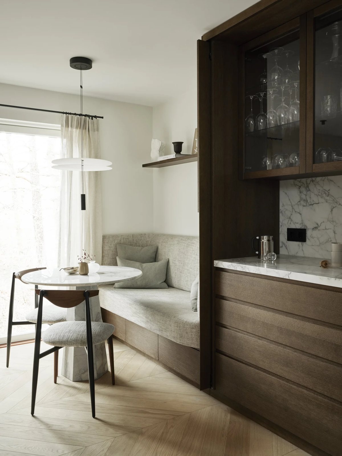 Breakfast corner with round marble table, textured fabric bench and wood accents