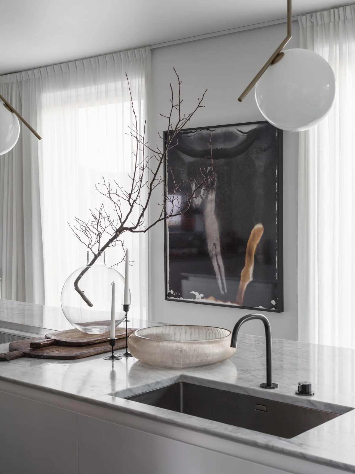 Minimalist kitchen featuring a white marble countertop, sculptural centerpiece, and modern art on the wall