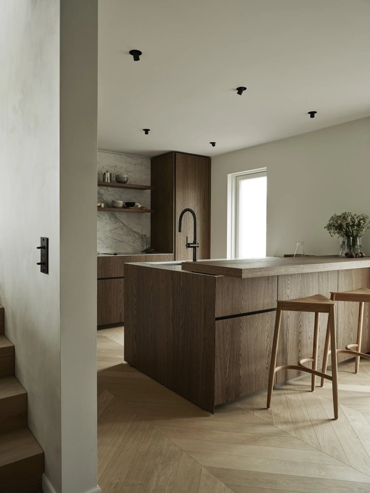 Modern kitchen island in dark oak with integrated seating and marble details