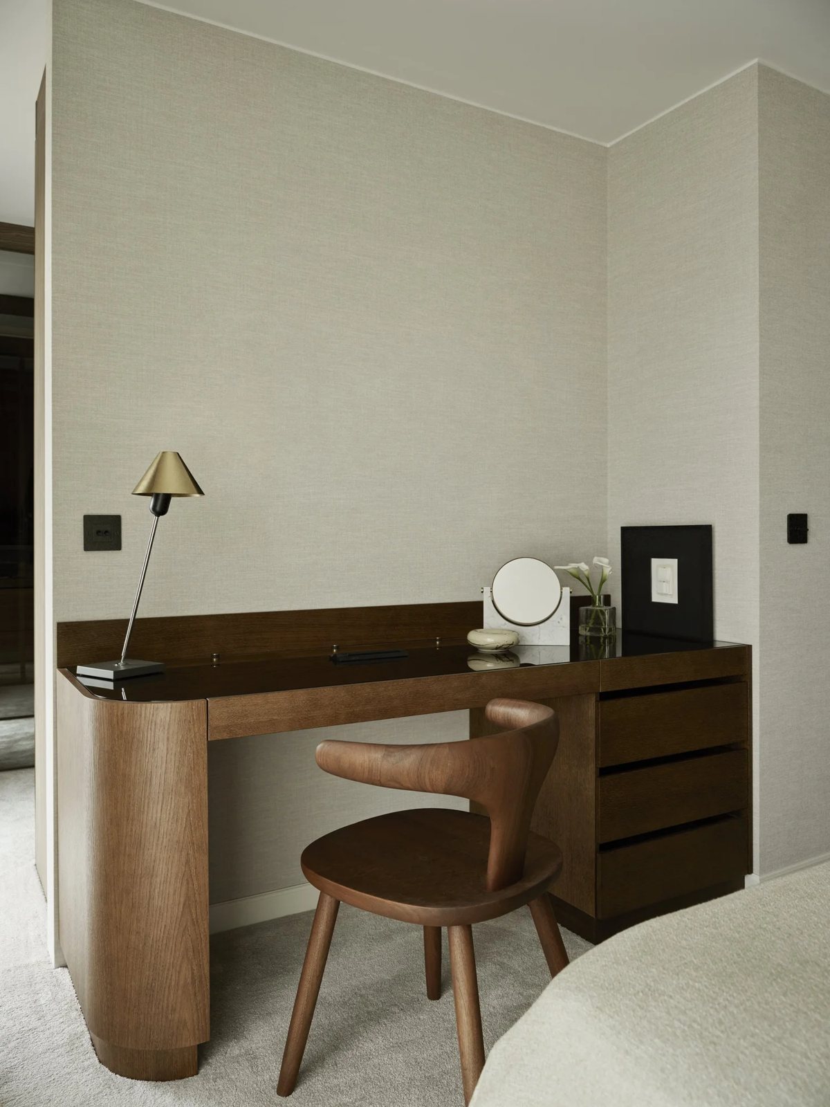 Custom vanity with curved wood details and sculptural design chair