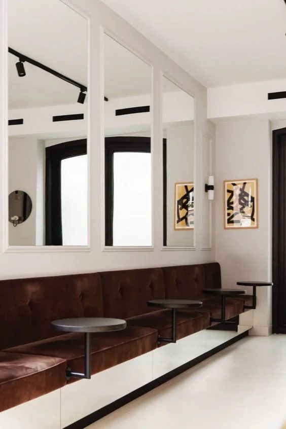 Velvet banquette and wall mirrors with black window frames.