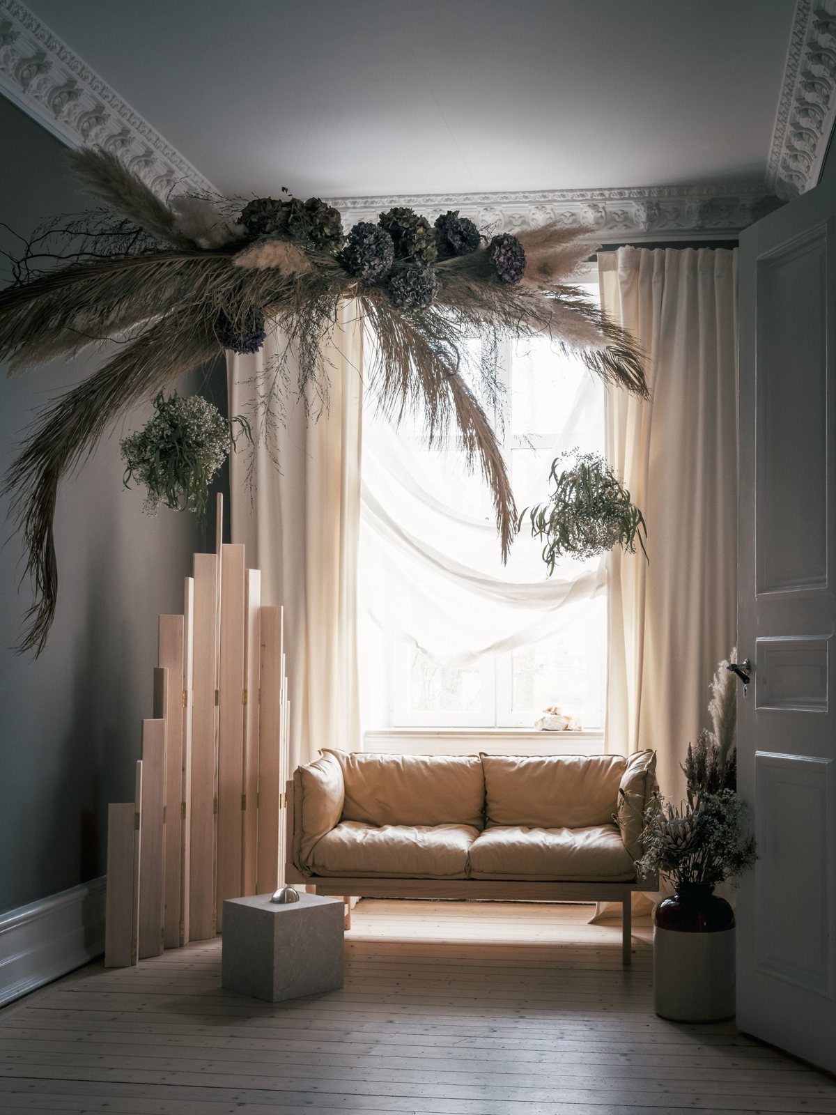 A floating floral installation above a soft leather sofa and wood accents.